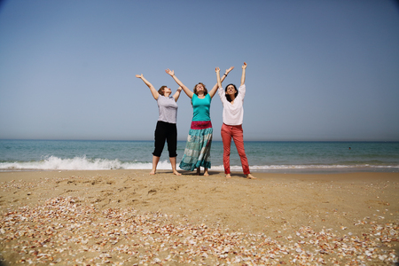 Portrait of three beautiful 40 years old women walking on seasideの写真素材