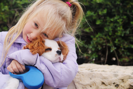 7 year old girl is walking with a puppy in the parkの写真素材