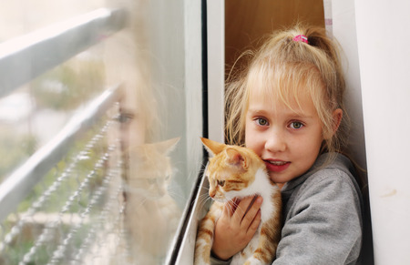 Portrait of a adorable little girl with red kittenの写真素材