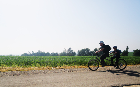 father and son ride a tandem bikeの写真素材