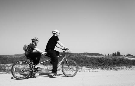 father and son ride a tandem bikeの写真素材