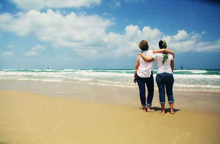 Portrait of two beautiful 45 years old women walking on seasideの写真素材