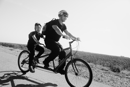 father and son ride a tandem bikeの写真素材