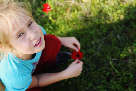 Cute 7 years old girl sitting in the spring green meadowの写真素材