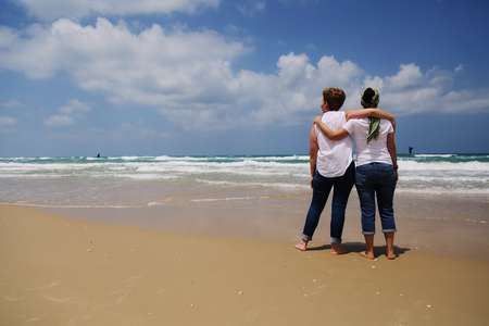 Portrait of two beautiful 40 years old women walking on seasideの写真素材