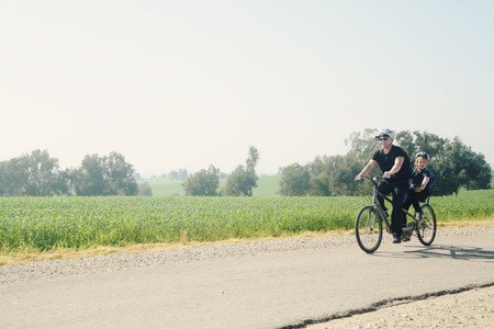 father and son ride a tandem bikeの写真素材