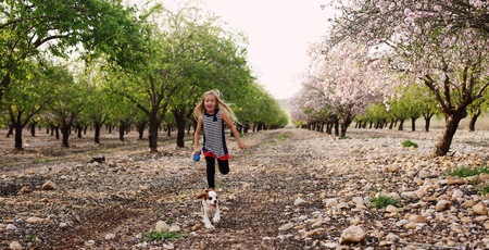 7 year old girl is walking with a puppy in the parkの写真素材