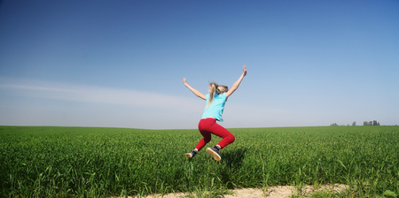 Cute girl ijumping in the fieldの写真素材