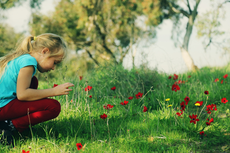Cute 7 years old girl sitting in the spring green meadowの写真素材