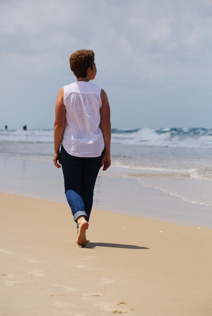 Portrait of beautiful 45 years old woman walking on seasideの写真素材