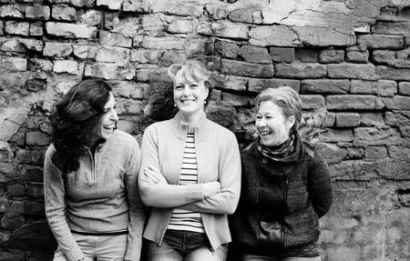 Outdoor portrait of three women standing next to the vintage wallの写真素材