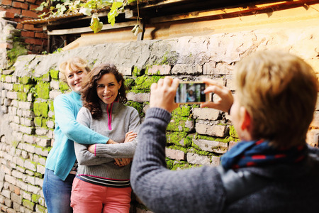 Outdoor portrait of three women standing next to the vintage wallの写真素材