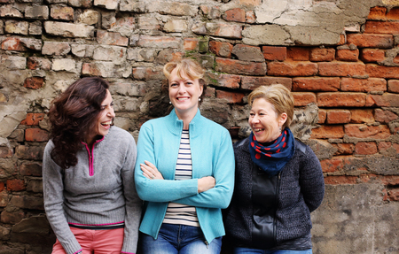 Outdoor portrait of three women standing next to the vintage wallの写真素材