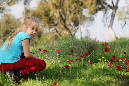 Cute 7 years old girl sitting in the spring green meadowの写真素材
