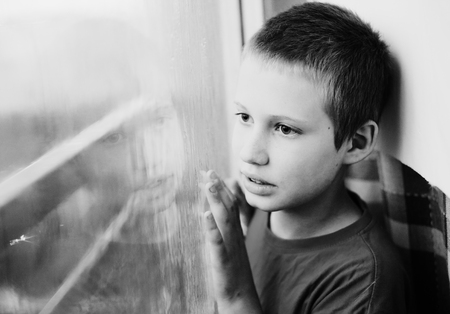 Cute 10 year old autistic boy looking at the rainの写真素材