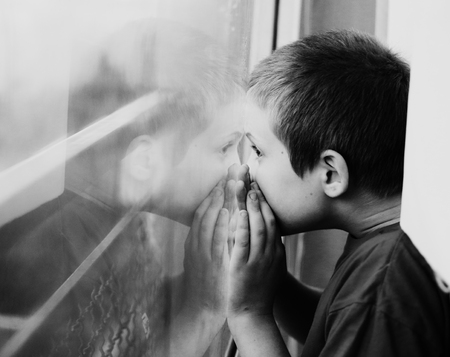 Cute 10 year old autistic boy looking at the rainの写真素材