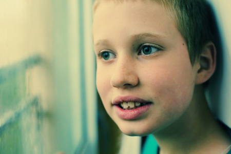 Cute 10 year old autistic boy looking at the rain