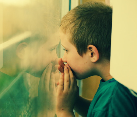 Cute 10 year old autistic boy looking at the rainの写真素材