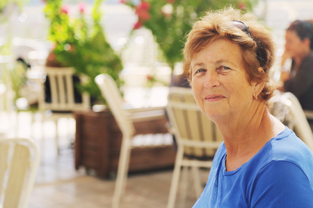 close up portrait of senior woman sitting in outdoor summer cafeの写真素材