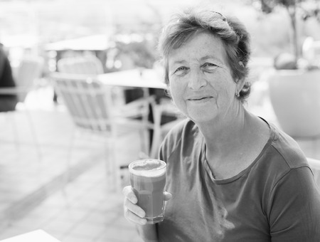 close up portrait of senior woman sitting in outdoor summer cafe