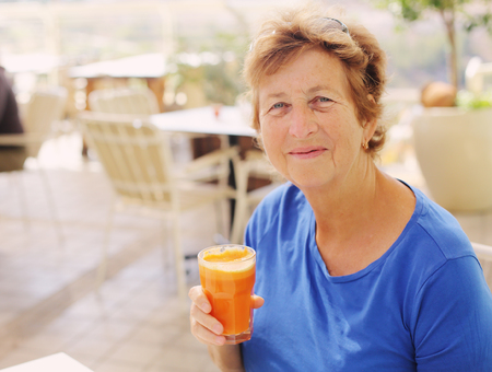 close up portrait of senior woman sitting in outdoor summer cafeの写真素材
