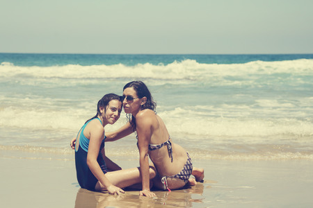 Mother and daughter having fun to spend time together on the beach at sunsetの写真素材