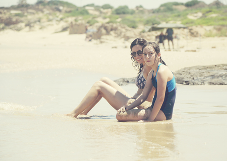 Mother and daughter having fun to spend time together on the beach at sunsetの写真素材