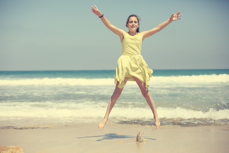 12 years old girl teen girl in yellow dress walking on seaside. Summer vacationの写真素材
