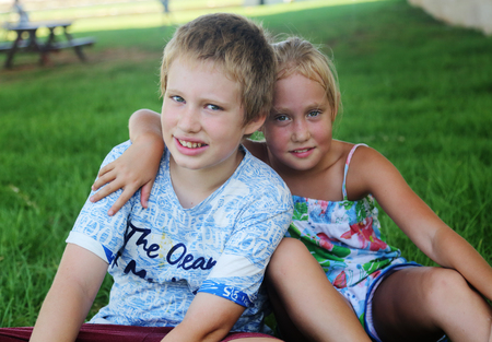 Portrait of happy 7 years old girl with her 10 years old autistic brother outdoorsの写真素材