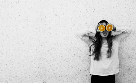 Portrait of beautiful teenage girl with orange fresh fruit outdoorの写真素材