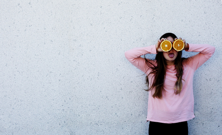 Portrait of beautiful teenage girl with orange fresh fruit outdoorの写真素材