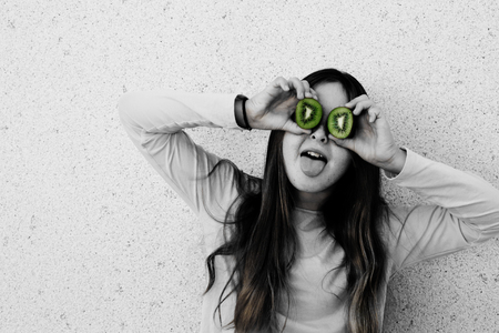 Portrait of beautiful teenage girl with kiwi fresh fruit outdoorの写真素材