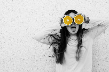 Portrait of beautiful teenage girl with orange fresh fruit outdoorの写真素材