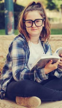 Portrait of tenage girl sitting outdoor reading a bookの写真素材
