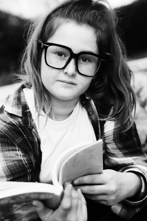 Portrait of tenage girl sitting outdoor with a bookの写真素材