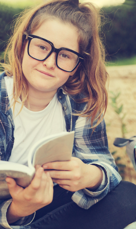 Portrait of tenage girl sitting outdoor with a bookの写真素材