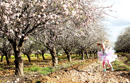 Outdoor portrait of girl in a unicorn costume. Spring is around, apple trees are blooming.の写真素材