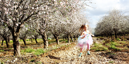 Girl in a unicorn costume jumps outdoors. Spring is around, apple trees are blooming.の写真素材