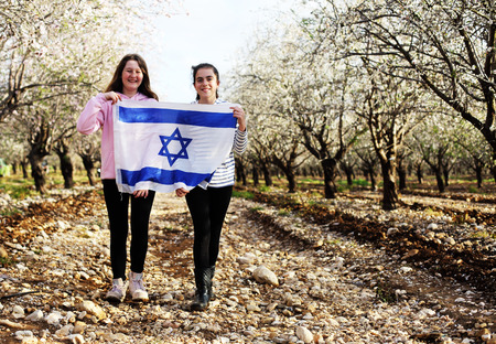 Two teenage girls are holding an Israeli flag outdoorsの写真素材