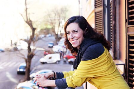 beautiful mature woman standing on the balcony looking to the streetの写真素材