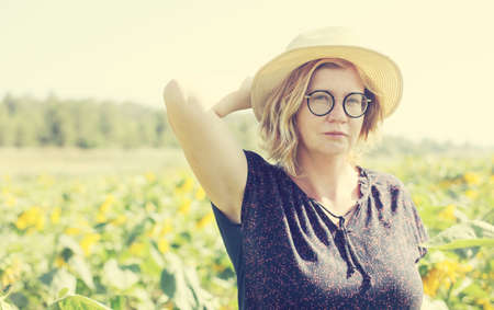 Portrait of happy mature woman with hat enjoying of freedom in the sunflowers fieldの写真素材