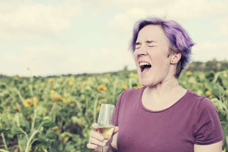 Beauty mature woman with sunflower enjoying freedom on summer sunflower fieldの写真素材