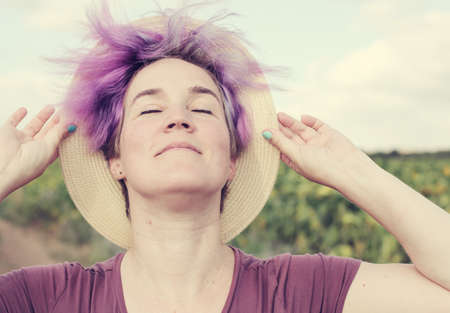 Beauty mature woman with sunflower enjoying freedom on summer sunflower fieldの写真素材