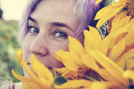 Beauty mature woman with sunflower enjoying freedom on summer sunflower fieldの写真素材