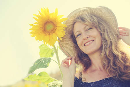 Portrait of happy mature woman  enjoying of freedom in the sunflowers fieldの写真素材