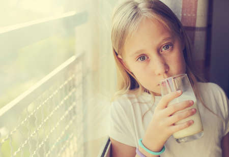 Cute girl drinking fresh organic milk . Healthy nutrition for small childrenの写真素材