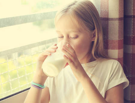 Cute girl drinking fresh organic milk . Healthy nutrition for small childrenの写真素材