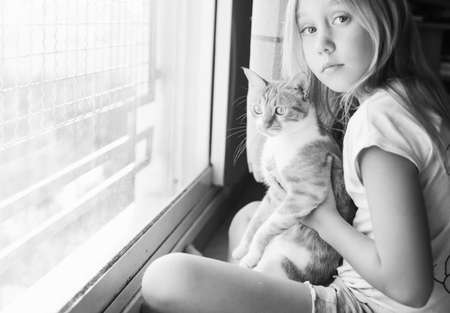 Portrait of a cute 9 years old girl with lovely red cat. Smiles and happinessの写真素材