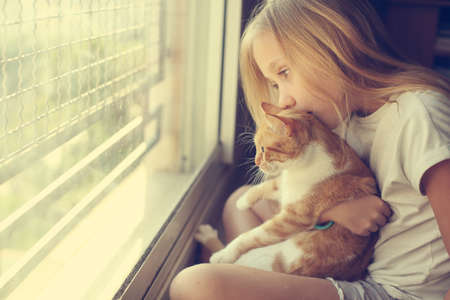 Portrait of a cute 9 years old girl with lovely red cat. Smiles and happinessの写真素材