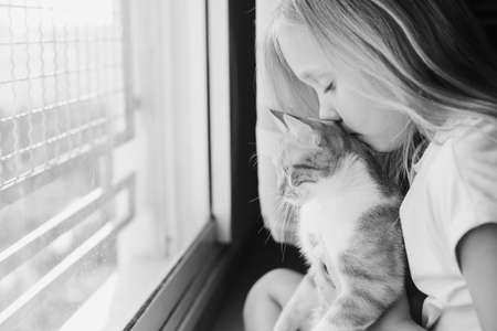 Portrait of a cute 9 years old girl with lovely red cat. Smiles and happinessの写真素材